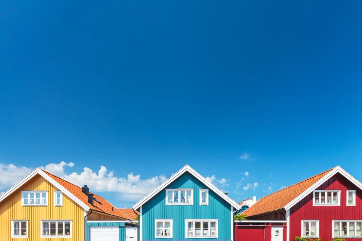 Rad av äldre trähus i gult, blått och rött mot en klarblå himmel