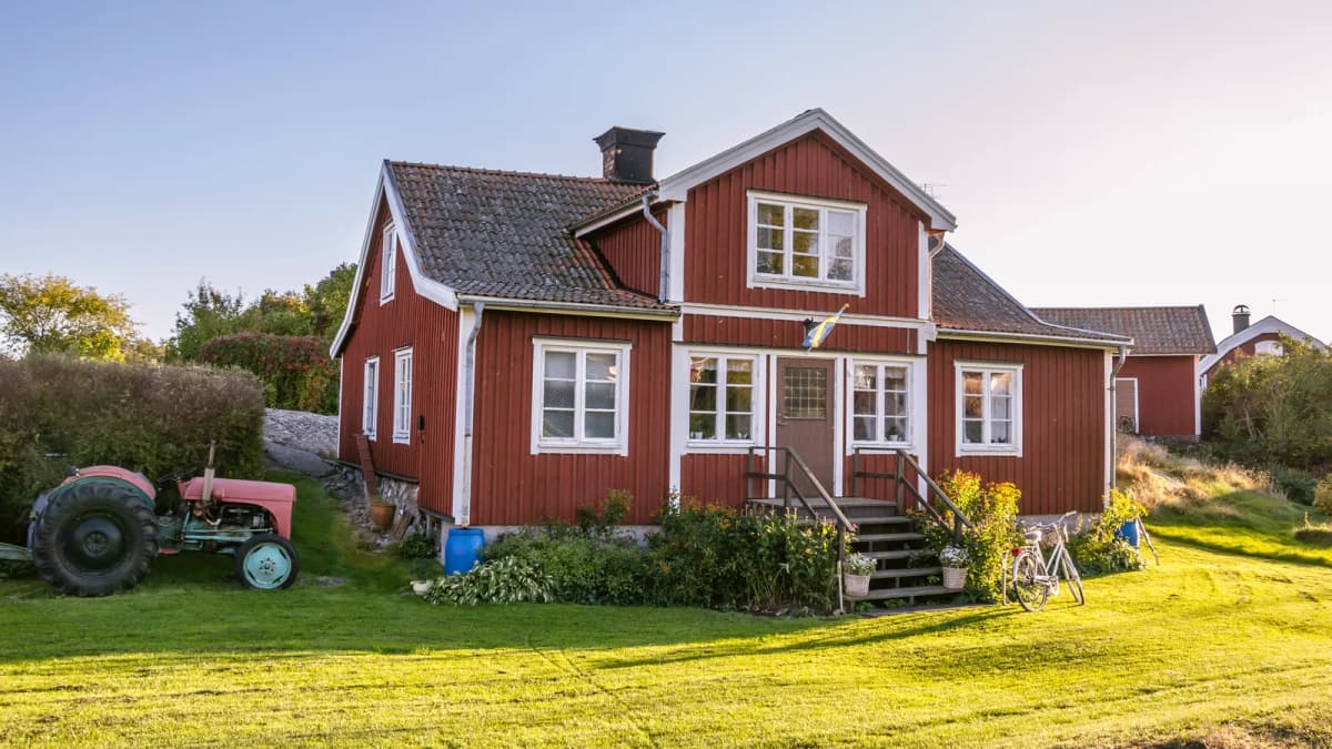 Röd trästuga med vita knutar på landet en solig sommarkväll